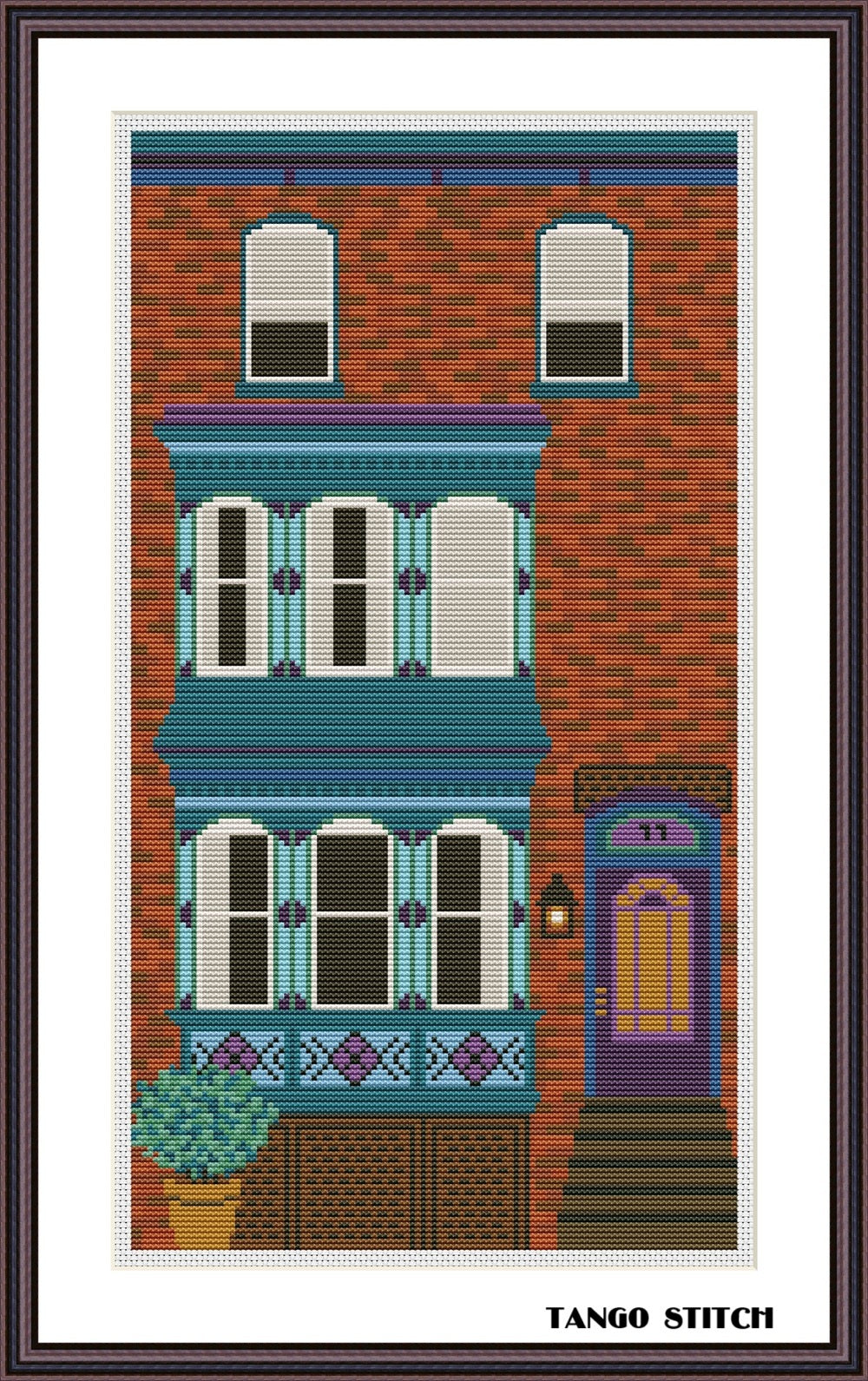 Cross-stitched depiction of a colorful building with windows and a door, framed by Tango Stitch.