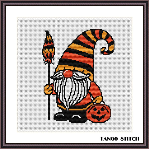 Halloween-themed gnome with striped hat and pumpkin, cross-stitch pattern on a white background. Halloween gnome festive spooky cross stitch pattern - Tango Stitch
