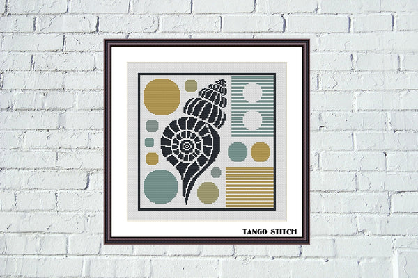 Framed artwork with a shell design on a white brick wall/ Sealife geometric cross stitch pattern - Tango Stitch